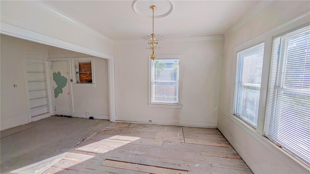 An empty room with unfinished wood flooring, white walls, a chandelier, and two windows — 852 4TH AVENUE N, ST PETERSBURG, FL