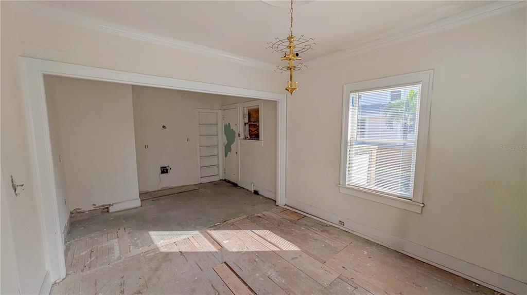 An unfinished room with exposed wood subflooring, a chandelier, and an adjacent smaller room — 852 4TH AVENUE N, ST PETERSBURG, FL