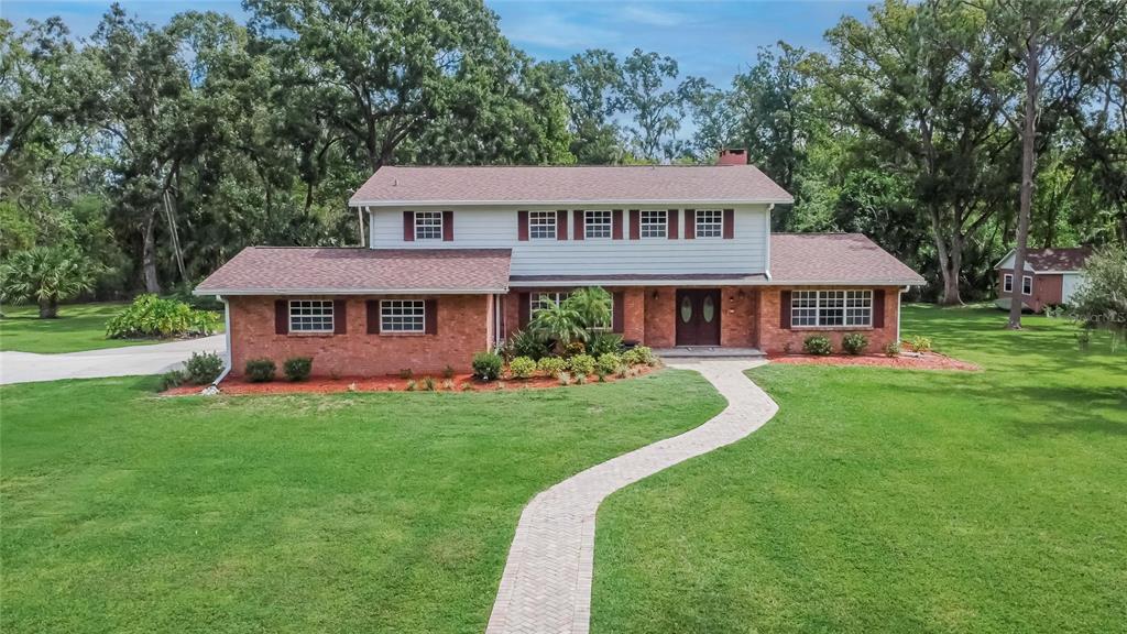 A two-story brick and siding house with a paved walkway sits on a grassy lawn — 1502 AZALEA STREET, PLANT CITY, FL