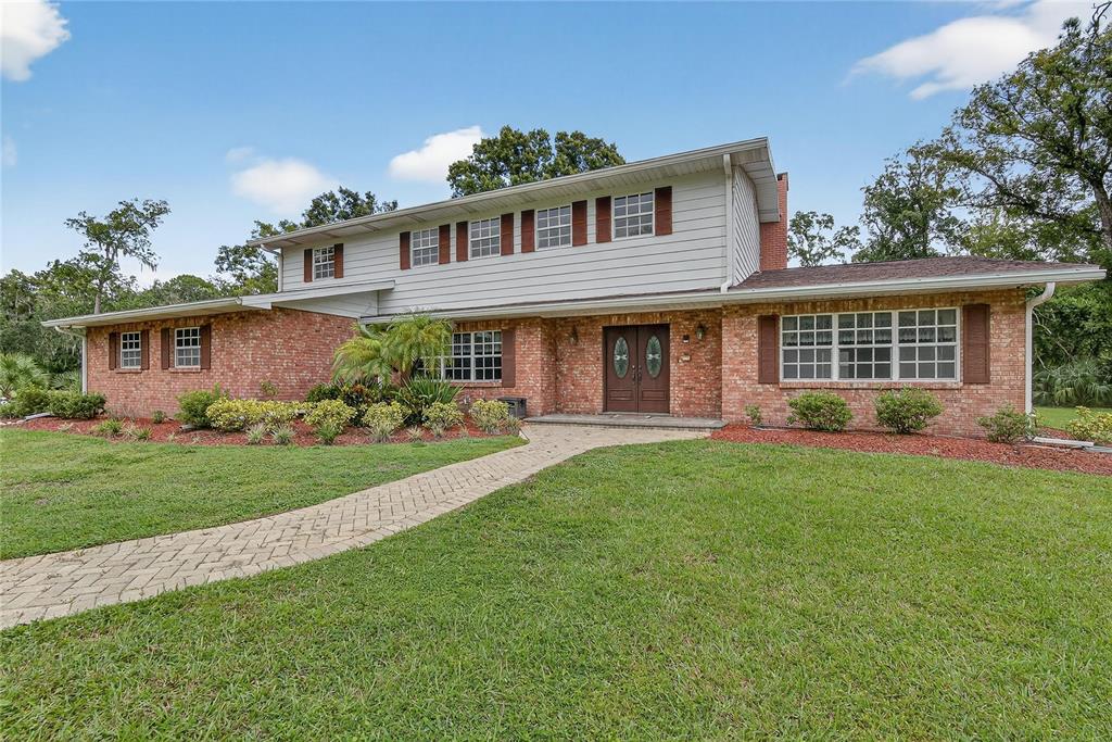 A two-story house with a brick and siding exterior, a paved walkway, and a front lawn — 1502 AZALEA STREET, PLANT CITY, FL