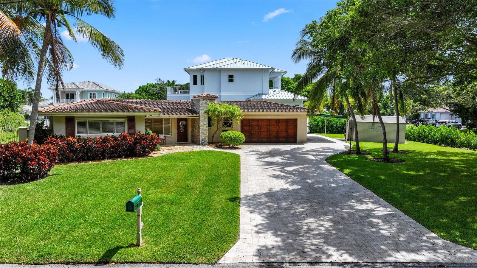 A two-story house with a tiled roof, stone chimney, and a paved driveway — 910 Banyan Drive, Delray Beach FL 33483, DELRAY BEACH, FL