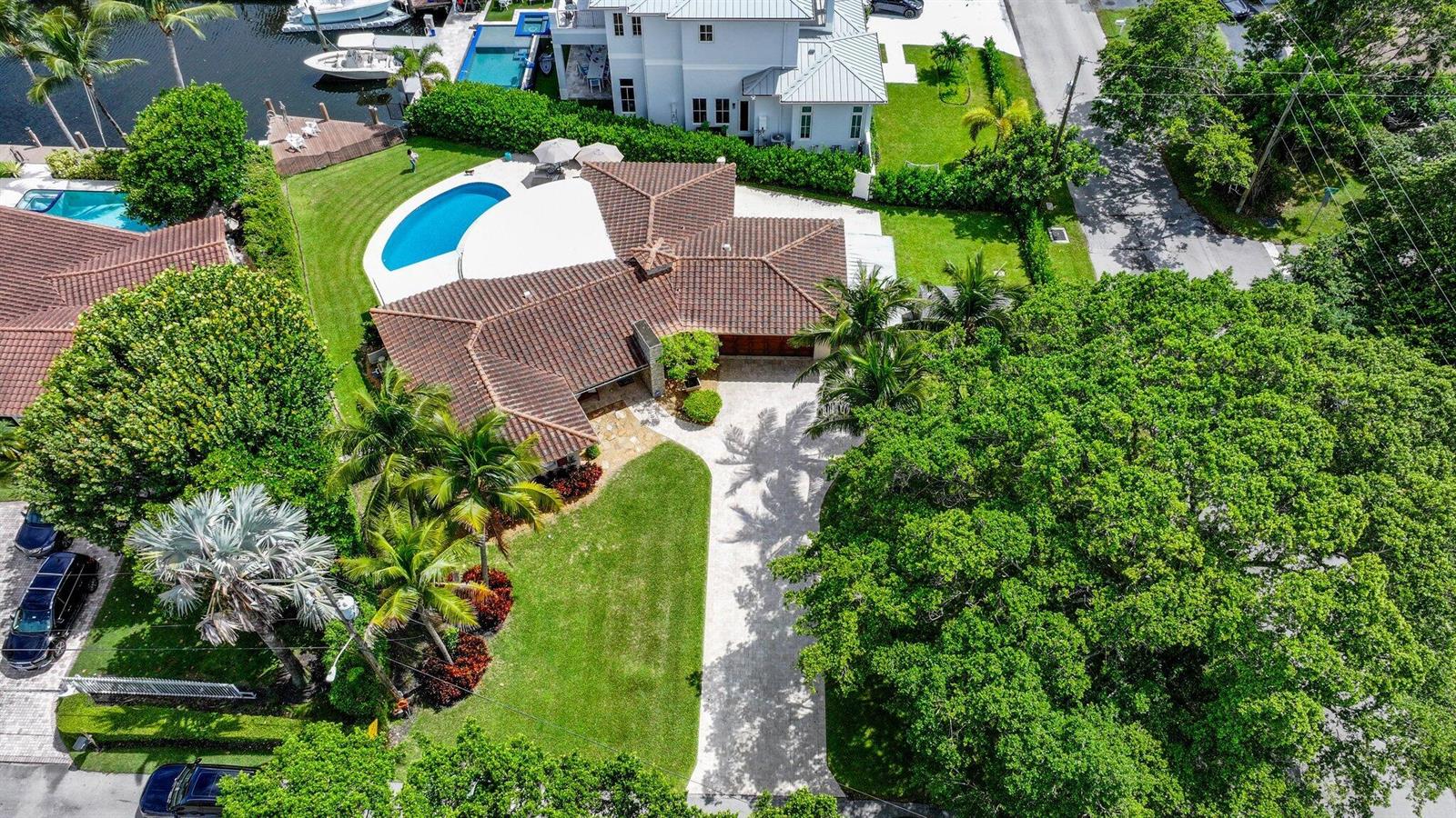 An aerial view shows a house with a tiled roof, swimming pool, and paved driveway — 910 Banyan Drive, Delray Beach FL 33483, DELRAY BEACH, FL