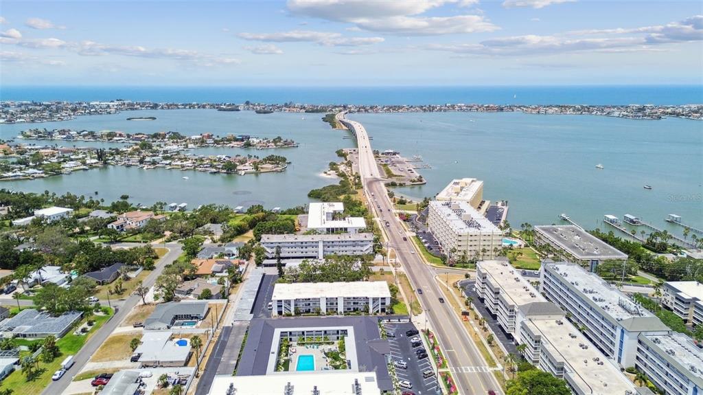 An aerial view shows apartment buildings, a road, and a bridge crossing a large bay — 2942 W BAY DRIVE UNIT 33, BELLEAIR BLUFFS, FL