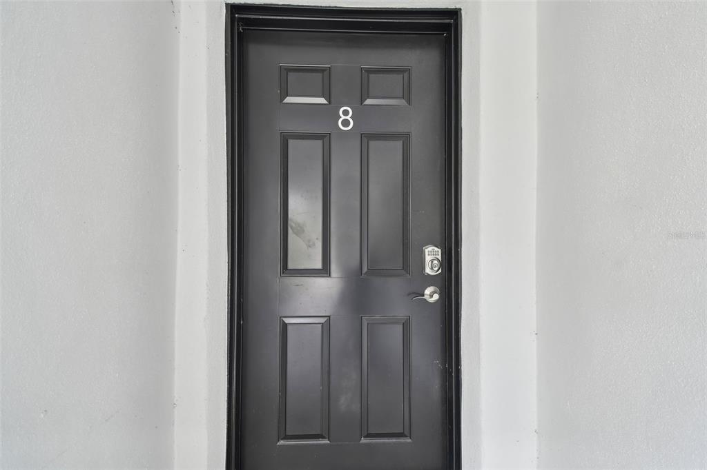 A black front door with the number eight on it is set into a white wall — 2942 W BAY DRIVE UNIT 33, BELLEAIR BLUFFS, FL