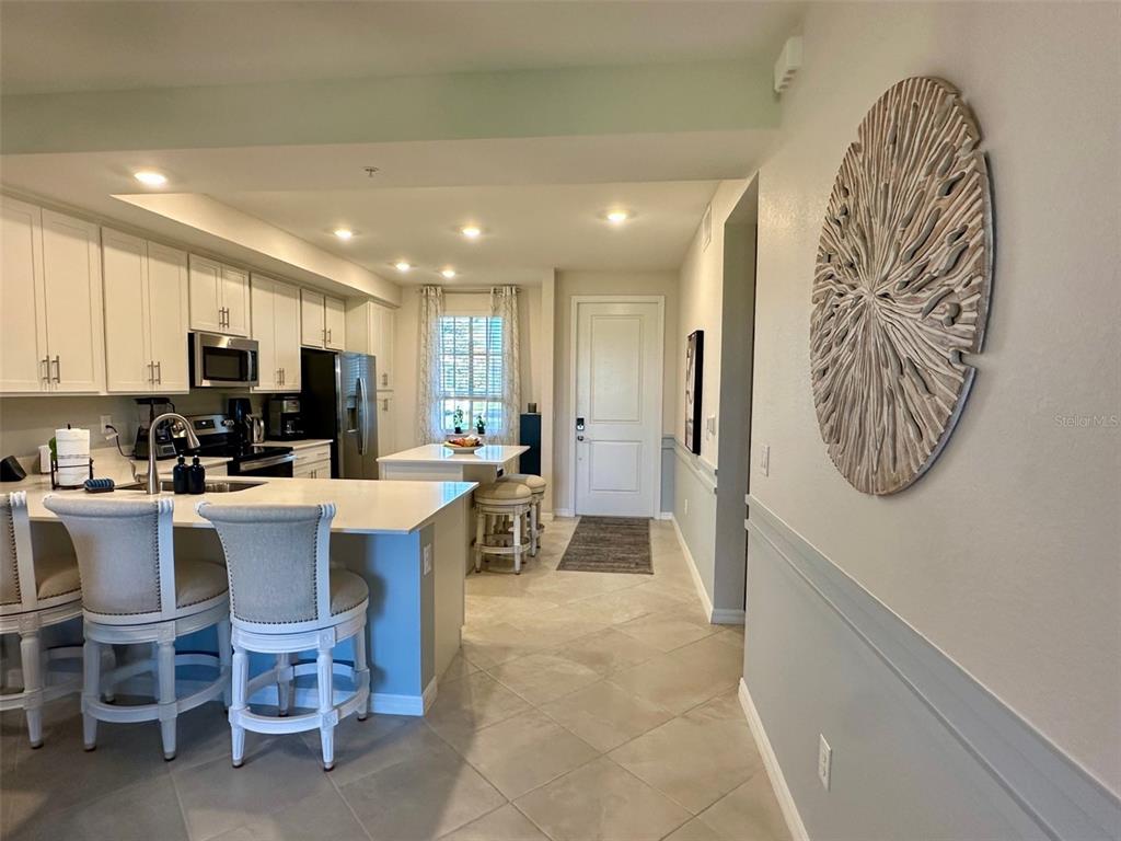 A kitchen with white cabinets, a breakfast bar, and a dining area near the entrance — 12280 WELLEN GOLF STREET UNIT 105, VENICE, FL
