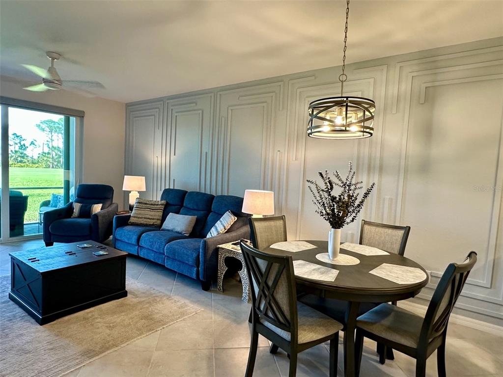 A living and dining area features blue furniture, a round table, and decorative wall molding — 12280 WELLEN GOLF STREET UNIT 105, VENICE, FL