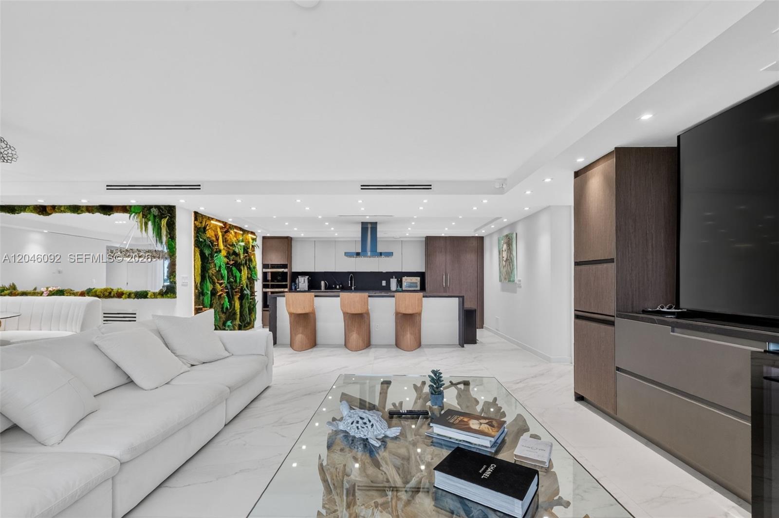 A modern open-concept living room and kitchen featuring white marble floors and a driftwood coffee table — 2301 Collins Ave # 443, Miami Beach FL 33139, MIAMI BEACH, FL