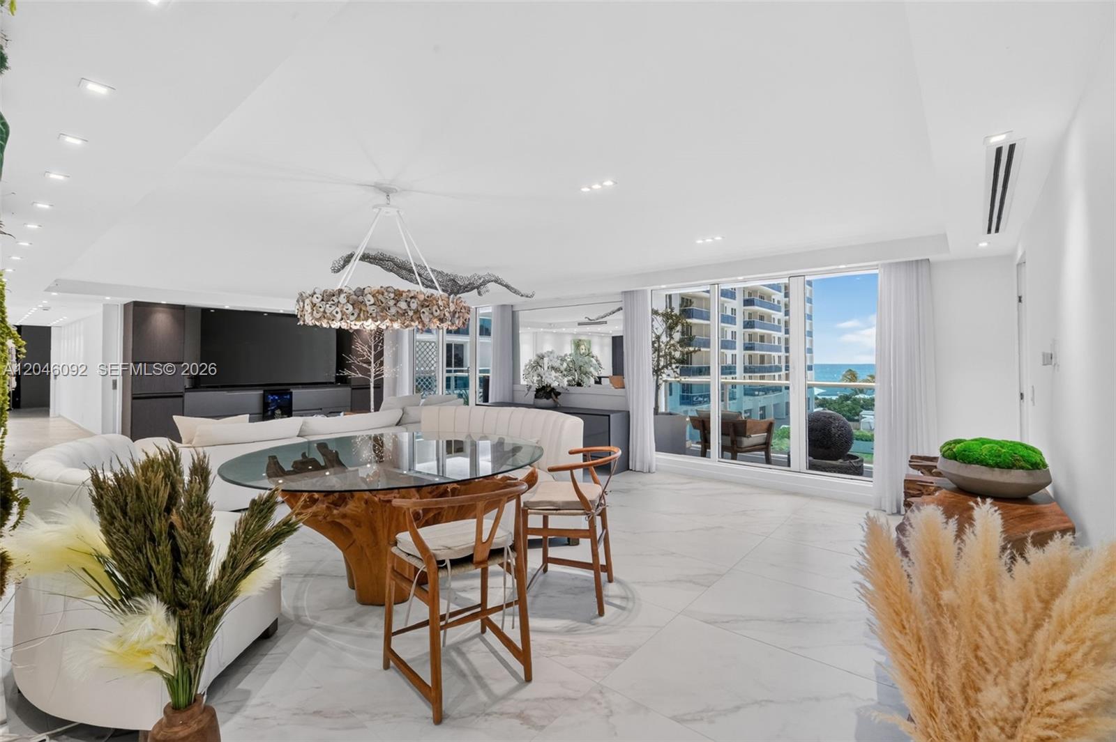 A modern dining area features a glass-topped wooden table, shell chandelier, and ocean views — 2301 Collins Ave # 443, Miami Beach FL 33139, MIAMI BEACH, FL