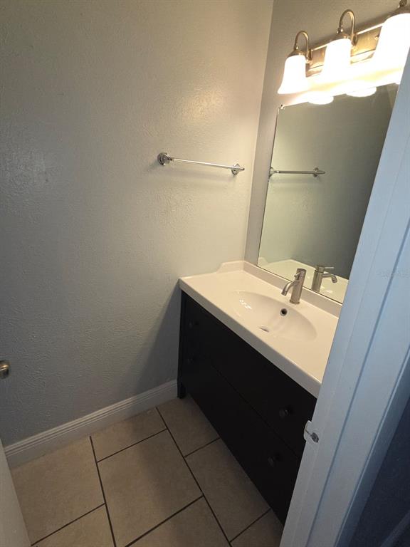 A bathroom features a dark vanity with a white sink, a mirror, and wall lighting — 4001 WOODFERN DRIVE UNIT C1, ORLANDO, FL