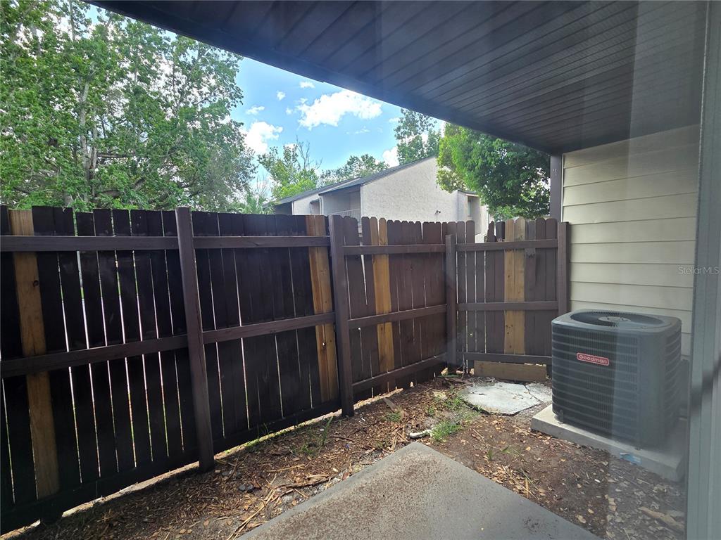A small patio features a wooden privacy fence and a Goodman air conditioning unit — 4001 WOODFERN DRIVE UNIT C1, ORLANDO, FL