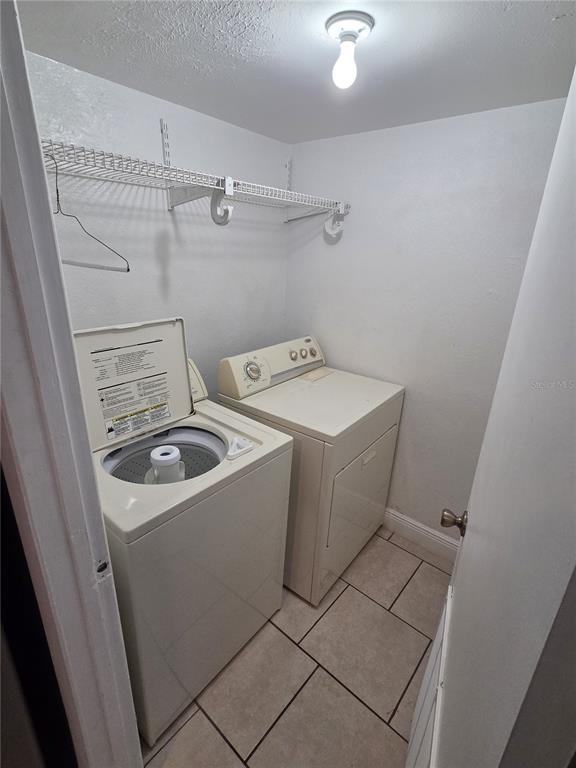 A laundry room with a top-loading washer, a dryer, and a wire shelf above — 4001 WOODFERN DRIVE UNIT C1, ORLANDO, FL