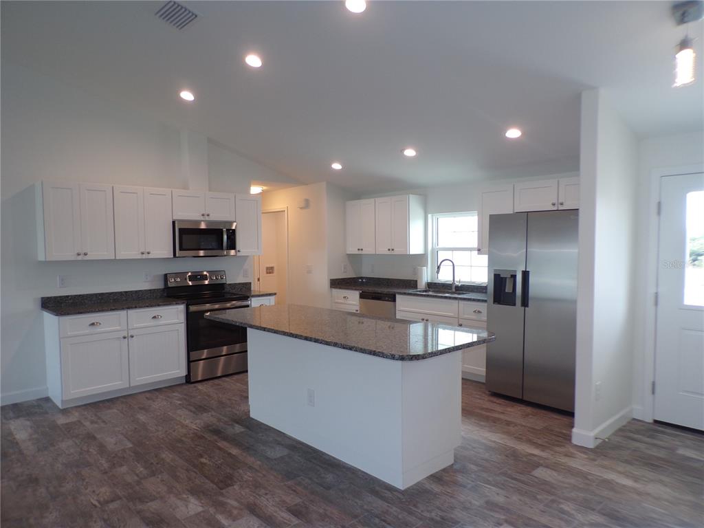 A kitchen features white cabinets, granite countertops, stainless steel appliances, and a central island — 3308 PORT CHARLOTTE BOULEVARD, PORT CHARLOTTE, FL