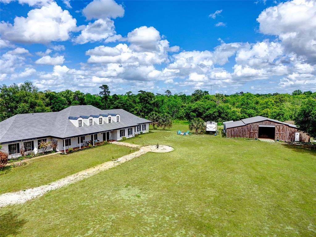 An aerial view shows a large house with a gray roof and a wooden barn — 5750 OAK HOLLOW LANE, OVIEDO, FL