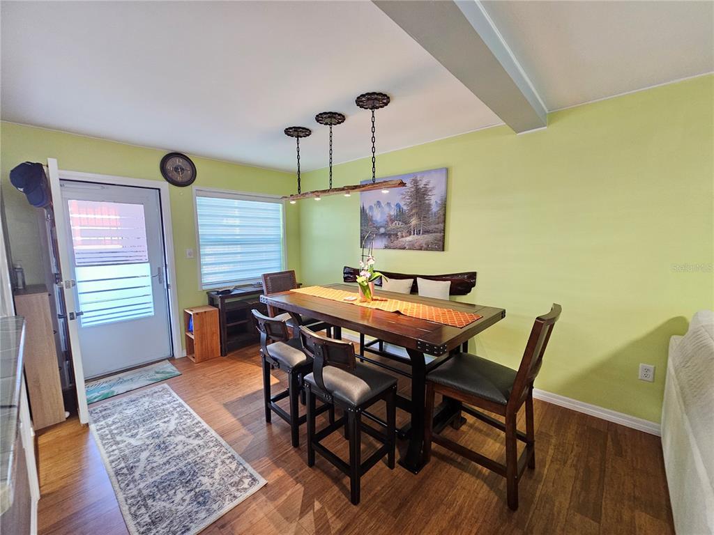 A dining room features a wooden table, four chairs, a bench, and a rustic light fixture — 5896 PALM LANE UNIT C27, BRADENTON, FL