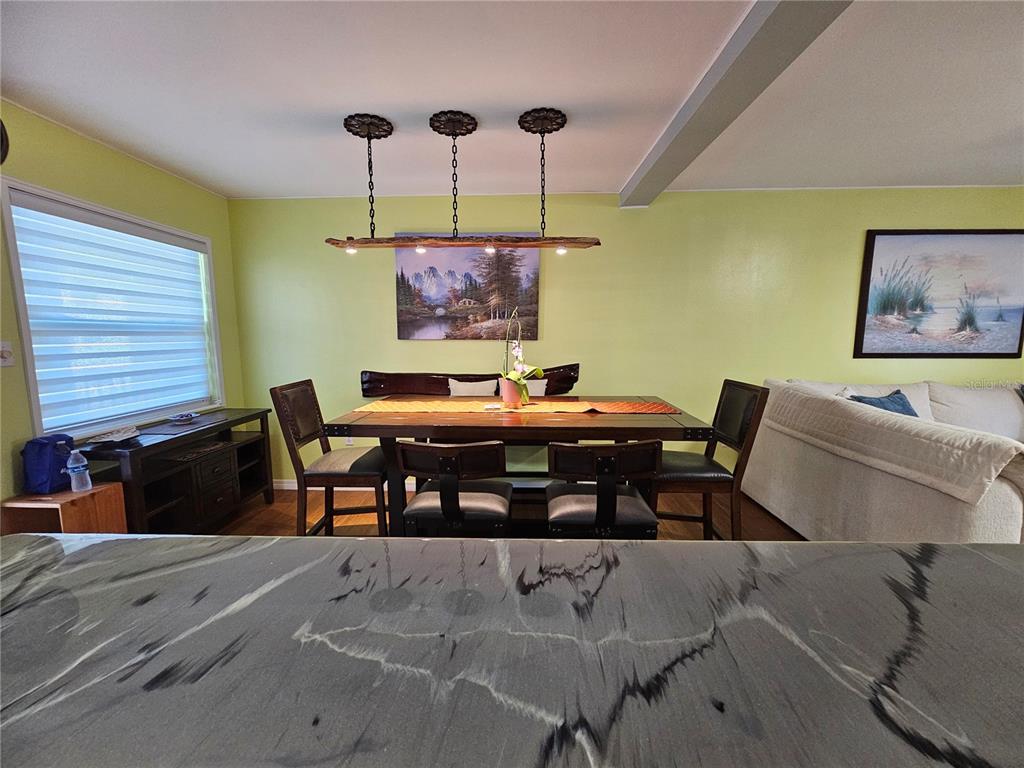A dining room features a wooden table, a bench, four chairs, and a hanging light fixture — 5896 PALM LANE UNIT C27, BRADENTON, FL