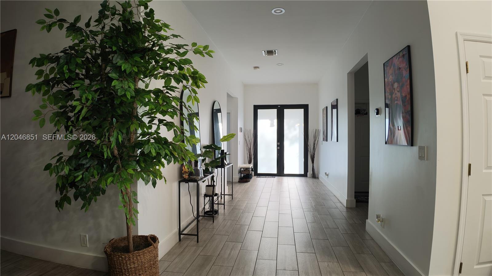 A bright entryway features light wood-look tile flooring, a large potted tree, and double doors — 1831 SW 48th Ave, West Park FL 33023, WEST PARK, FL