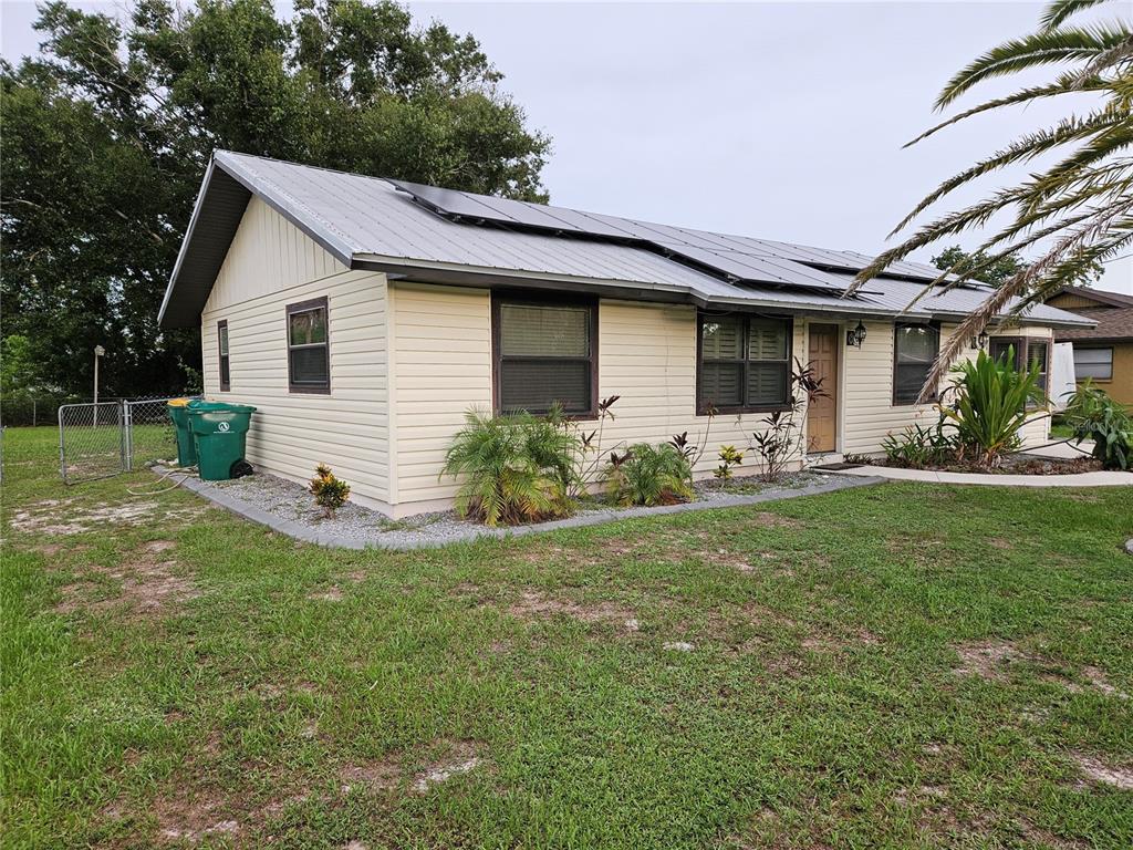 A single-story house with light siding, a metal roof with solar panels, and landscaping — 6270 SPINNAKER BOULEVARD, ENGLEWOOD, FL