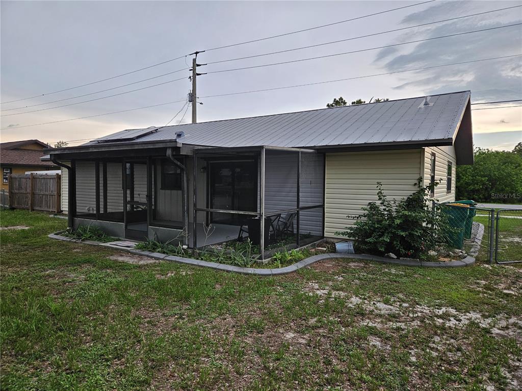 A single-story house with a metal roof and a screened-in porch in the backyard — 6270 SPINNAKER BOULEVARD, ENGLEWOOD, FL