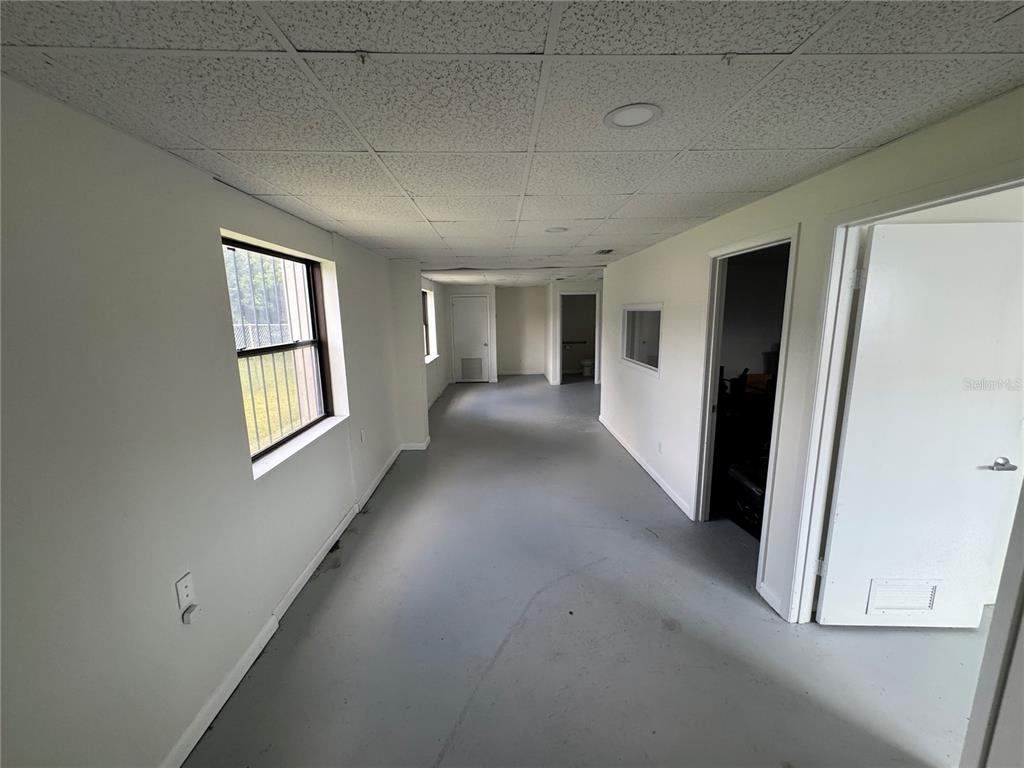 A long, narrow office space features white walls, a gray floor, and a drop ceiling — 702 W PARK AVENUE UNIT A1, EDGEWATER, FL
