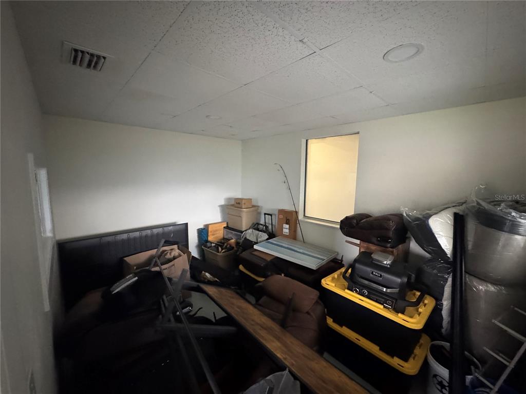 A cluttered room with white walls, a drop ceiling, and a small window — 702 W PARK AVENUE UNIT A1, EDGEWATER, FL