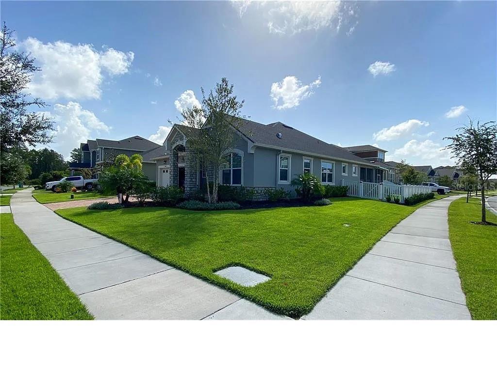 A single-story suburban house with a gray exterior, stone accents, and a manicured lawn — 7902 CORKFIELD AVENUE, ORLANDO, FL
