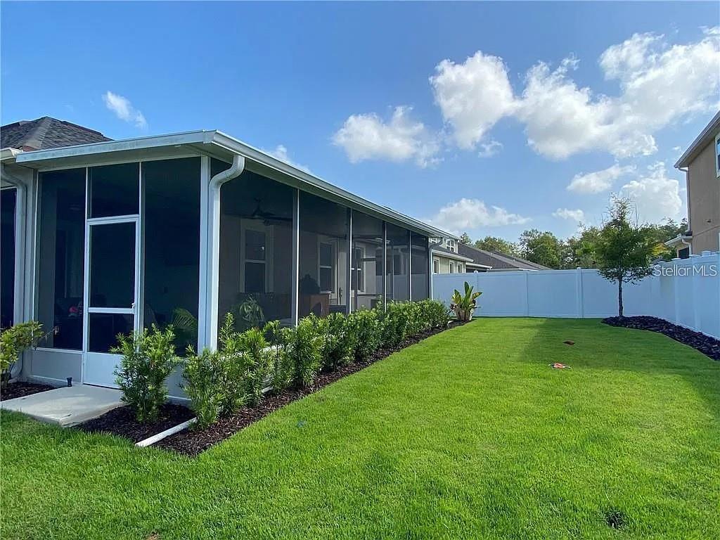 A screened-in porch overlooks a grassy backyard enclosed by a white vinyl fence — 7902 CORKFIELD AVENUE, ORLANDO, FL