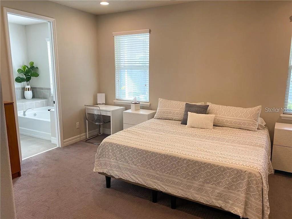 A bedroom features a bed with patterned bedding, a small desk, and an attached bathroom — 7902 CORKFIELD AVENUE, ORLANDO, FL