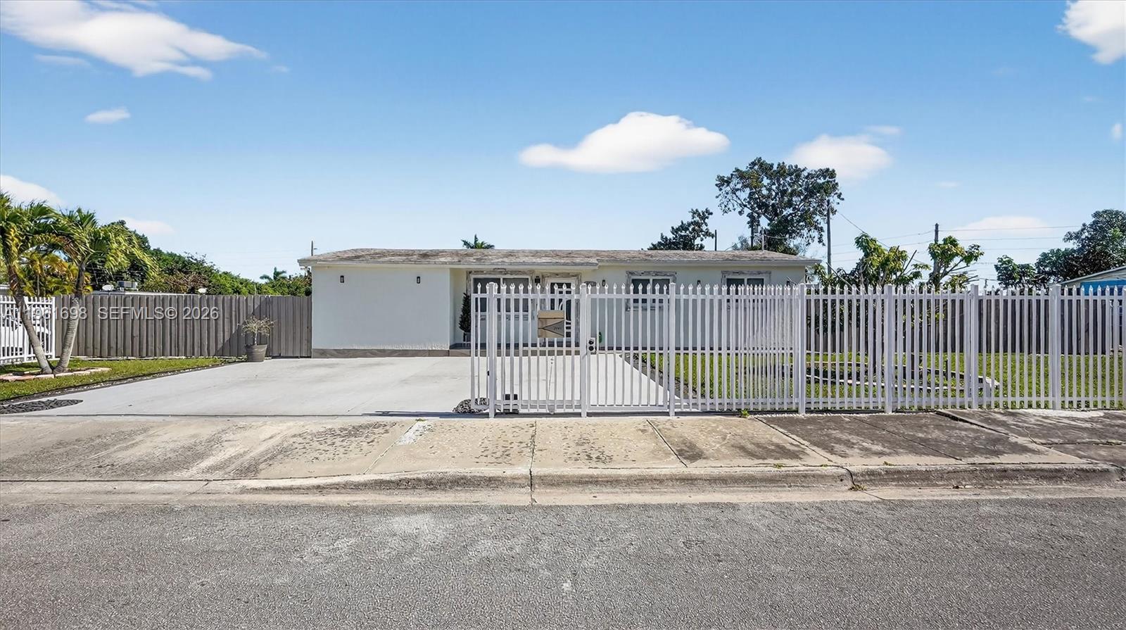 A single-story house with a white exterior, a concrete driveway, and a white metal fence — 22301 SW 117th Pl, Miami FL 33170, MIAMI, FL