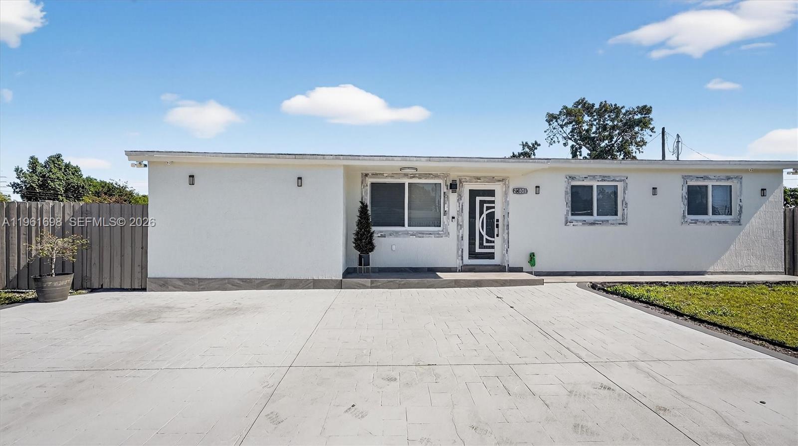 A single-story house with a white exterior, a paved driveway, and a modern front door — 22301 SW 117th Pl, Miami FL 33170, MIAMI, FL