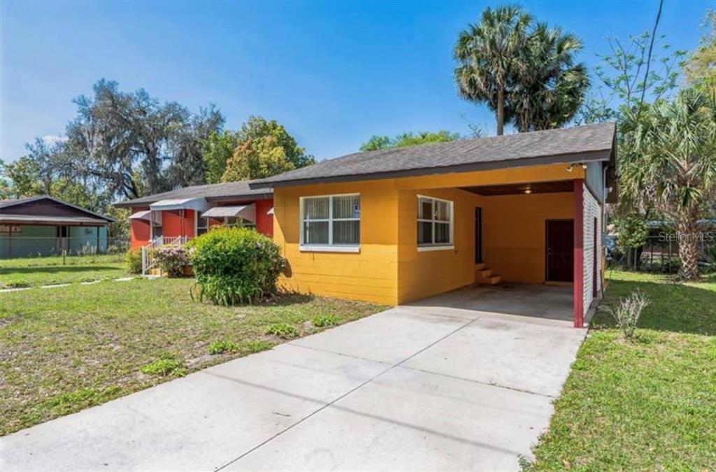 A single-story house with a yellow exterior, a concrete driveway, and an attached carport — 612 KENSINGTON STREET, EUSTIS, FL