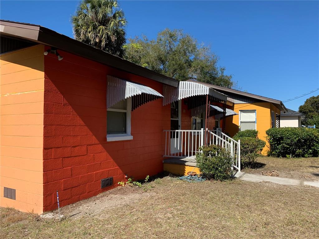 A bright orange concrete block house features metal window awnings and a small front porch — 612 KENSINGTON STREET, EUSTIS, FL
