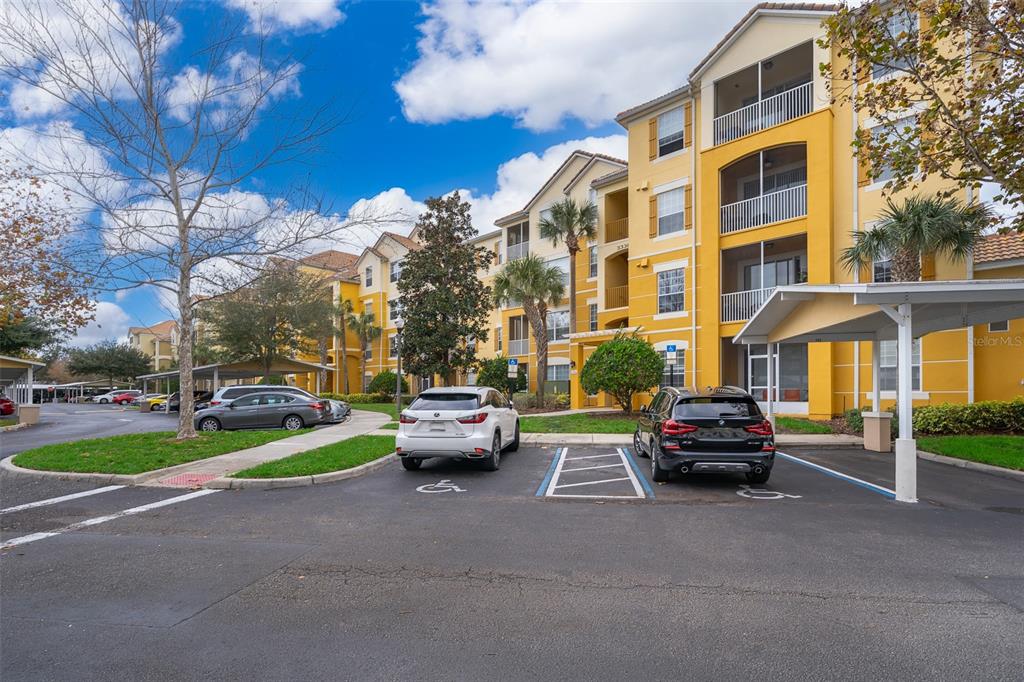 A yellow multi-story apartment building with a parking lot and two handicap spaces in front — 3338 ROBERT TRENT JONES DRIVE UNIT 106, ORLANDO, FL