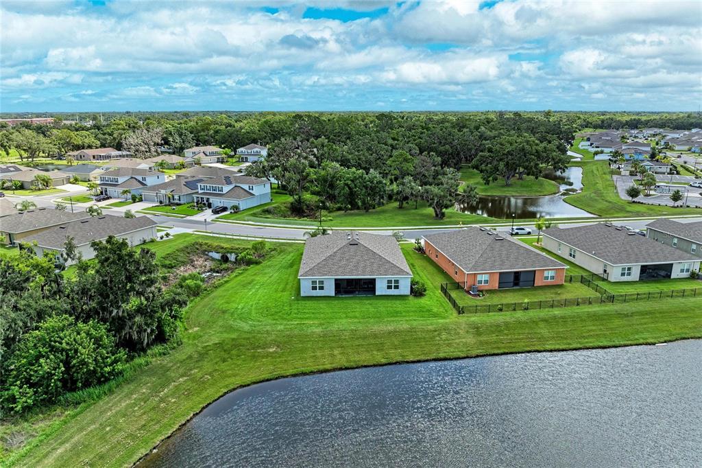 An aerial view shows several suburban houses situated near a pond and wooded area — 6421 114TH AVENUE E, PARRISH, FL