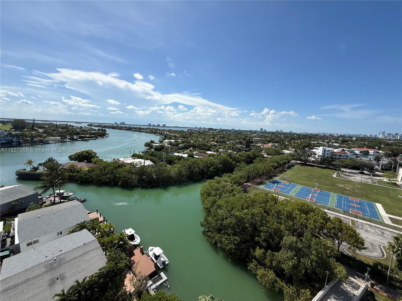 An aerial view shows a waterway, residential homes, and a basketball court — 7441 Wayne Ave # 10E, Miami Beach FL 33141, MIAMI BEACH, FL
