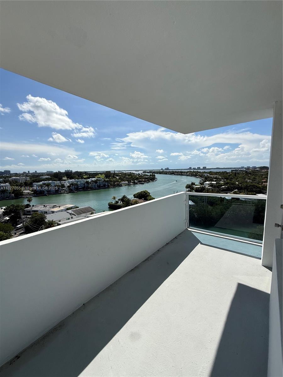 A balcony with a glass railing overlooks a waterway and a coastal cityscape — 7441 Wayne Ave # 10E, Miami Beach FL 33141, MIAMI BEACH, FL