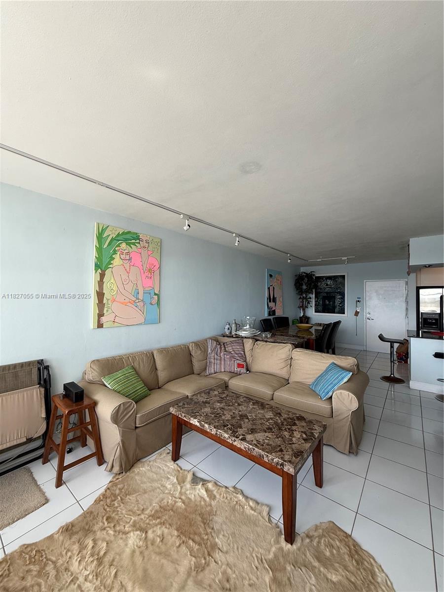 A living room features a beige sectional sofa, a marble coffee table, and tile flooring — 7441 Wayne Ave # 10E, Miami Beach FL 33141, MIAMI BEACH, FL