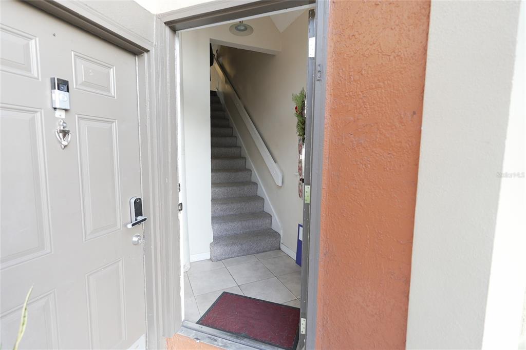 An open front door reveals a tiled entryway leading to a carpeted staircase — 409 FOUNTAINHEAD CIRCLE UNIT 236, KISSIMMEE, FL