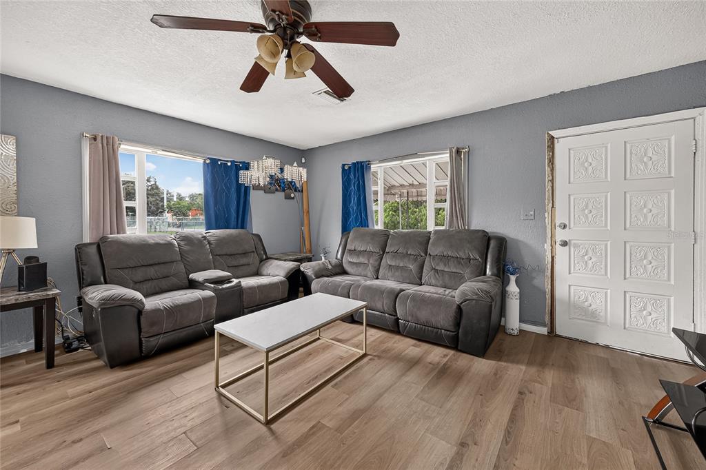 A living room with gray walls, two gray sofas, a coffee table, and wood flooring — 804 E FLORA STREET, TAMPA, FL