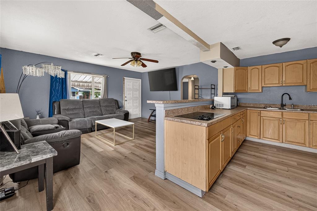 An open-concept living room and kitchen featuring wood-look flooring, light wood cabinets, and gray walls — 804 E FLORA STREET, TAMPA, FL