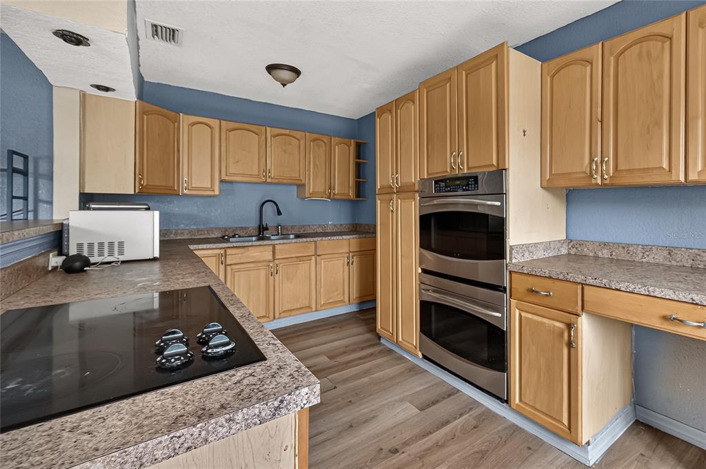 A kitchen with wood cabinets, stainless steel double ovens, and a dark laminate countertop — 804 E FLORA STREET, TAMPA, FL