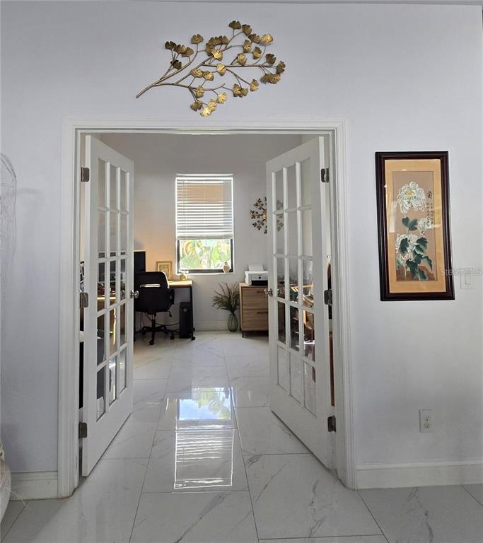 A home office is visible through open French doors, featuring white tile floors and a window — 1819 NW 21ST STREET, CAPE CORAL, FL