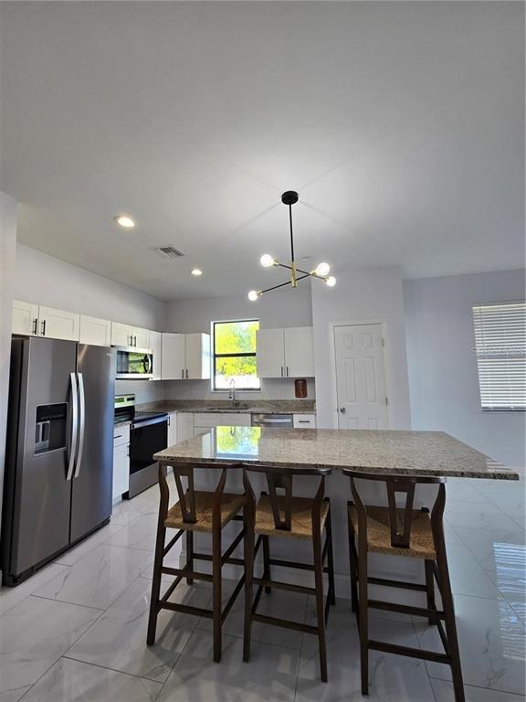 A kitchen features white cabinets, granite countertops, stainless steel appliances, and a central island — 1819 NW 21ST STREET, CAPE CORAL, FL