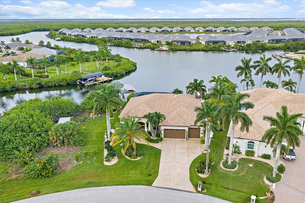 An aerial view of a suburban house with a tile roof, driveway, and waterfront backyard — 15172 LEIPZIG CIRCLE, PORT CHARLOTTE, FL