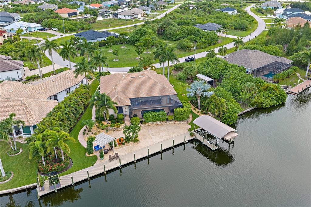 An aerial view shows a waterfront house with a pool cage, boat dock, and lift — 15172 LEIPZIG CIRCLE, PORT CHARLOTTE, FL