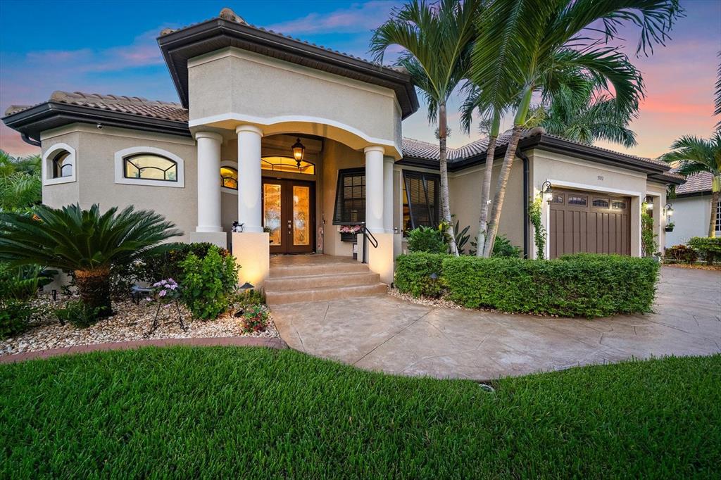 A beige single-story house with a tiled roof, arched entryway, and a landscaped front yard — 15172 LEIPZIG CIRCLE, PORT CHARLOTTE, FL