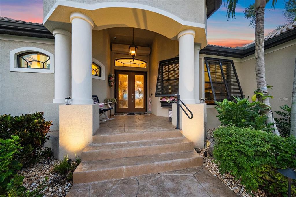 The exterior entrance of a house features a covered porch with columns and double doors — 15172 LEIPZIG CIRCLE, PORT CHARLOTTE, FL