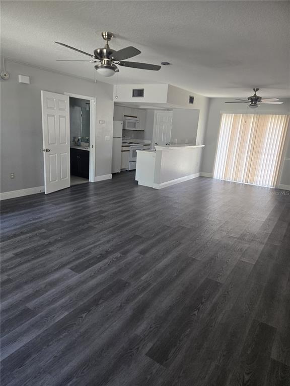 An open-concept living area features gray wood-look flooring, two ceiling fans, and a kitchen — 718 FLORIDA PALMS COURT, KISSIMMEE, FL