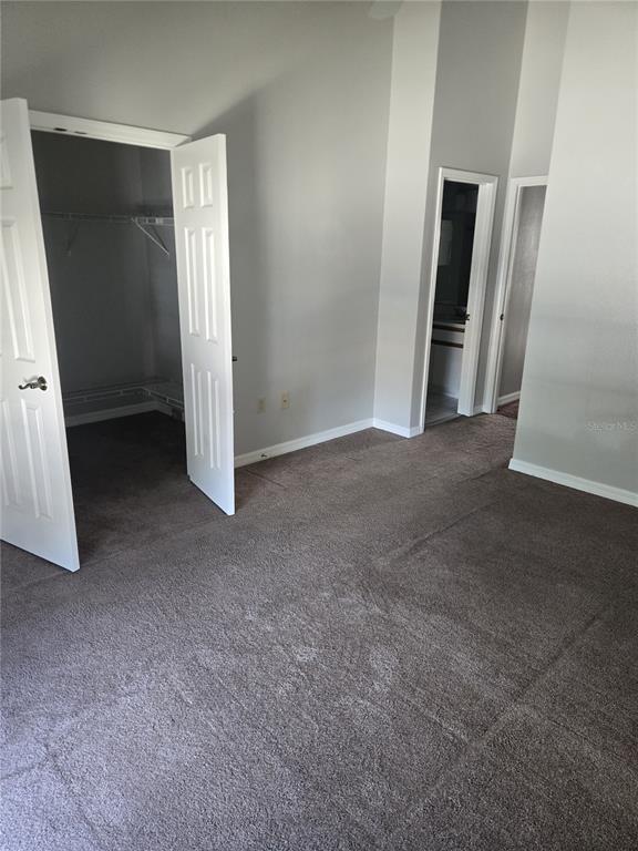 A bedroom with gray carpet, light gray walls, a walk-in closet, and two doorways — 718 FLORIDA PALMS COURT, KISSIMMEE, FL