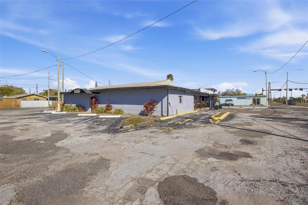 A gray commercial building with a parking lot and a black awning under a blue sky — 4900 66TH STREET N, ST PETERSBURG, FL