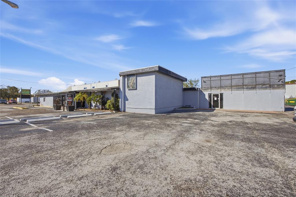 A low-rise commercial building with a gray stucco exterior and a large asphalt parking lot — 4900 66TH STREET N, ST PETERSBURG, FL